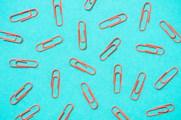 full frame of arranged red paper clips on blue background