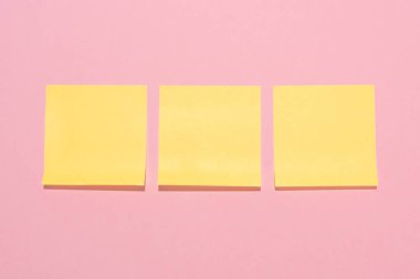 top view of blank yellow stick it notes placed in row on pink  clipart