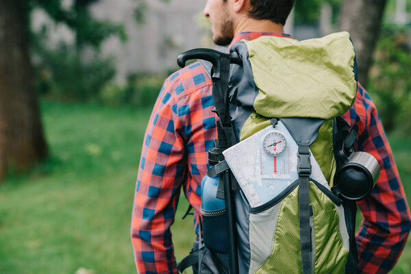 cropped shot of young man traveler with backpack, compass and map