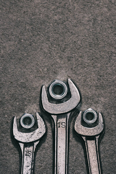 top view of wrenches and nuts on grey surface