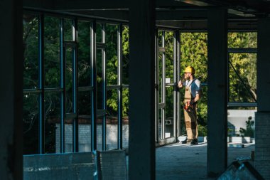 uzak builder koruyucu kask ve Insaat sitesinde Smartphone cep telefonu ile konuşurken googles'görünümünü 