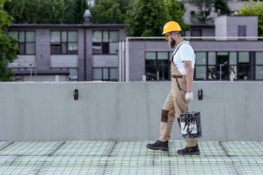 builder koruyucu kask ve çimento inşaat sahasında kova taşıyan googles'yan görünüm 