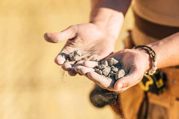 cropped image of construction worker holding stones in hand palms 
