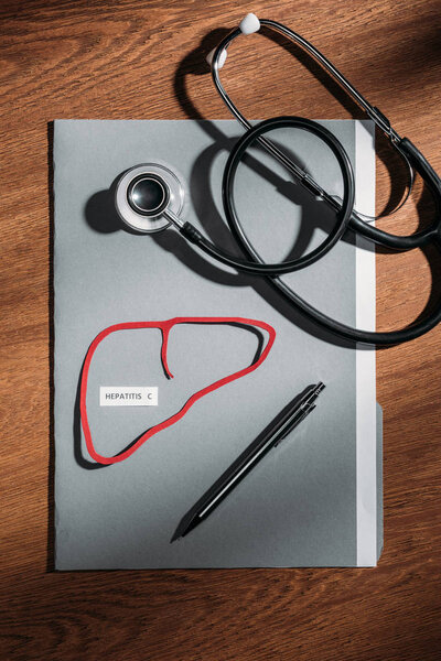 top view of folder, stethoscope, and liver with lettering hepatitis c on table, world hepatitis day concept