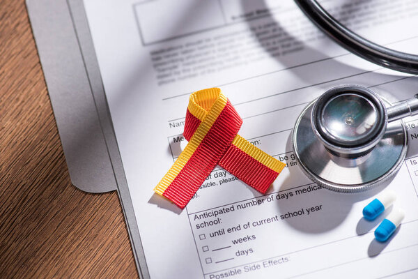 selective focus of ribbon, stethoscope, pills and medical questionary, world hepatitis day concept