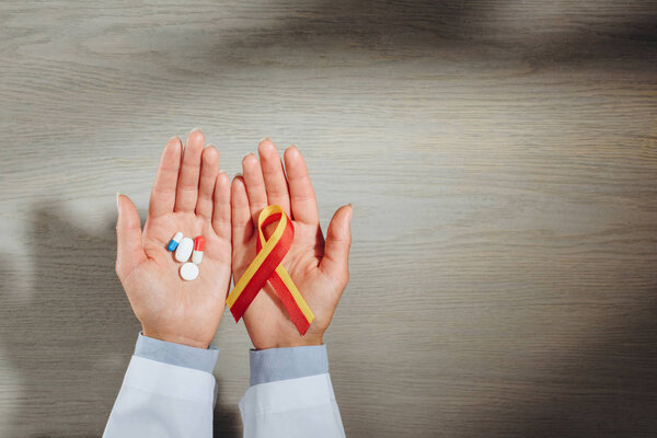 cropped image of female doctor holding ribbon and pills, world hepatitis day concept