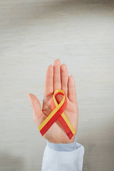 cropped image of female doctor holding ribbon over table, world hepatitis day concept