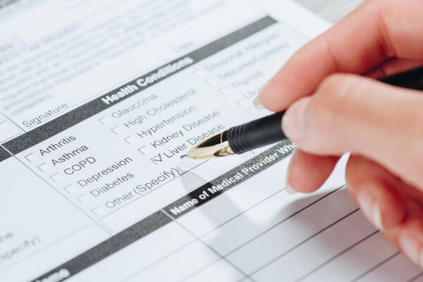 cropped image of woman marking liver disease in medical questionary, world hepatitis day concept