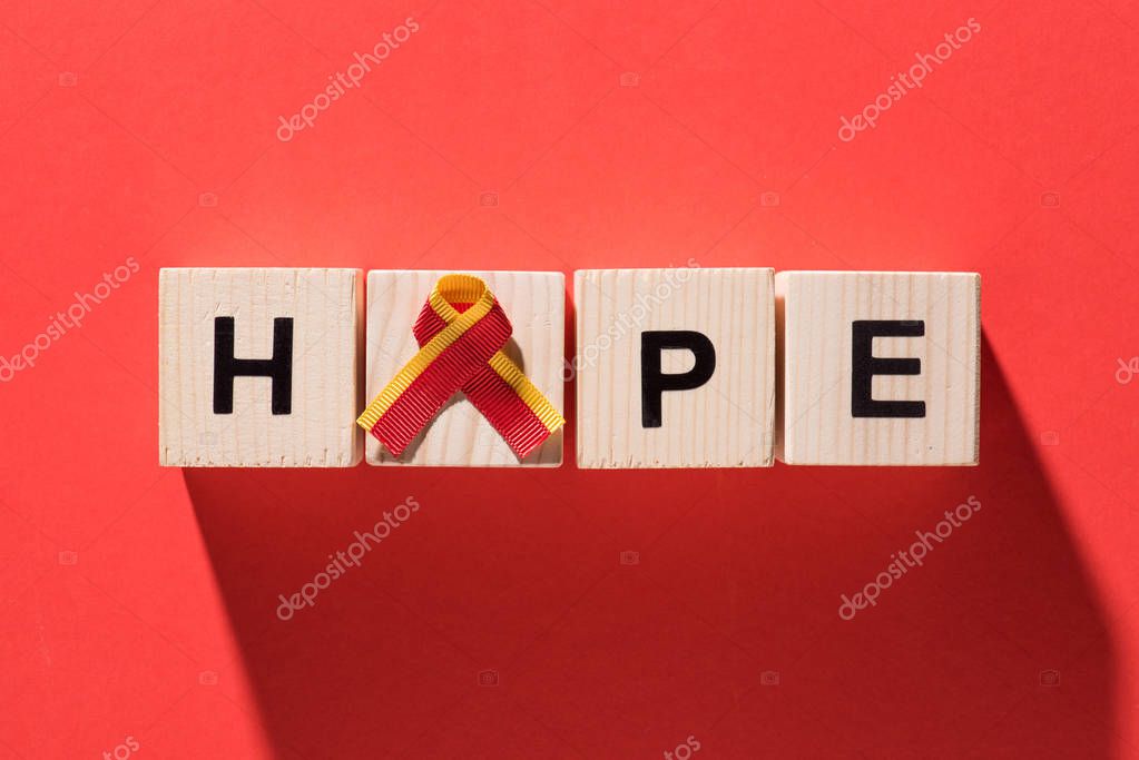 Top view of ribbon and lettering hope from wooden cubes on red background, world hepatitis day concept