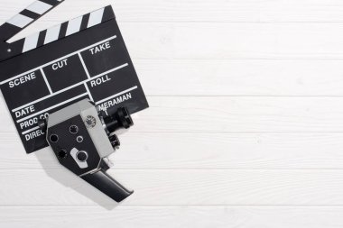 flat lay with clapper board and retro camera on white wooden tabletop clipart