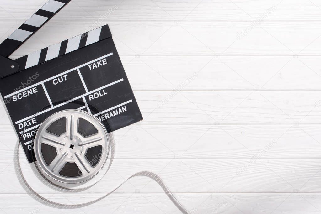 flat lay with clapper board and filmstrips on white wooden tabletop