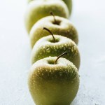 Nahaufnahme von grünen Äpfeln mit Wassertropfen auf weißem Hintergrund Nahaufnahme von grünen Äpfeln mit Wassertropfen auf weißem Hintergrund