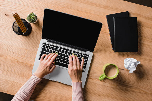 cropped shot of businesswoman typing on laptop at workplace