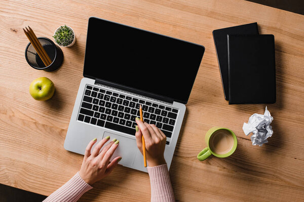 cropped shot of businesswoman pointing at laptop screen with pencil at workplace