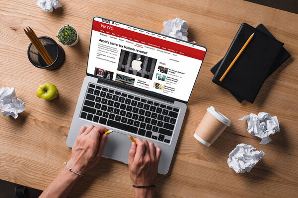 cropped shot of businessman breaking pencil at workplace while looking at bbc website on screen of laptop