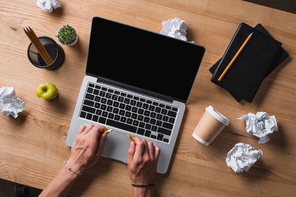 cropped shot of businessman breaking pencil at workplace with laptop and crumpled papers