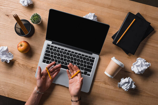 cropped shot of businessman holding broken pencil halves in hands at workplace