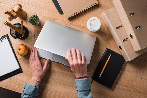 обрезанный снимок бизнесмена, открывающего ноутбук на рабочем месте
