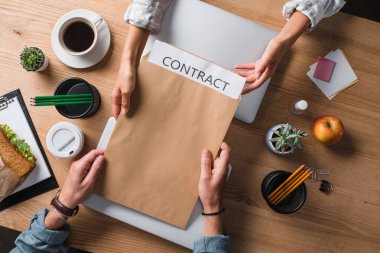 cropped shot of businesspeople passing contract in envelope at workplace clipart