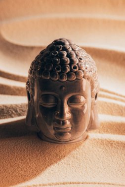 close up view of buddha sculpture on sandy beach clipart