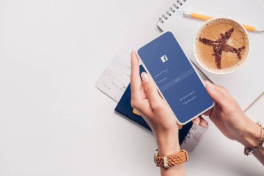 smartphone ile facebook logo üstünde perde, Masa üstü kadınla bardak fincan kahve, Bilet ve pasaport ile kırpılmış