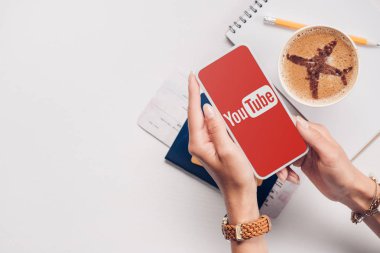 kadın youtube logo üstünde perde, Masa üstü ile smartphone ile atış fincan kahve, Bilet ve pasaport ile kırpılmış