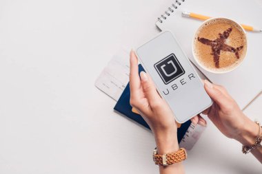 smartphone uber logo üstünde perde, Masa üstü ile kadınla bardak fincan kahve, Bilet ve pasaport ile kırpılmış