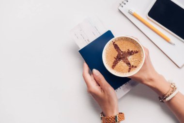 kırpılmış bardak kahve masa bilet, pasaport, smartphone ile tabelaya uçak ile tutan kadın kavramı seyahat