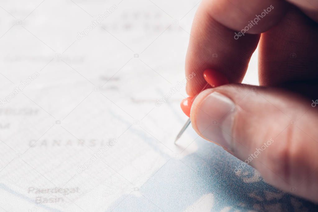 partial view of man putting pin on map, traveling concept