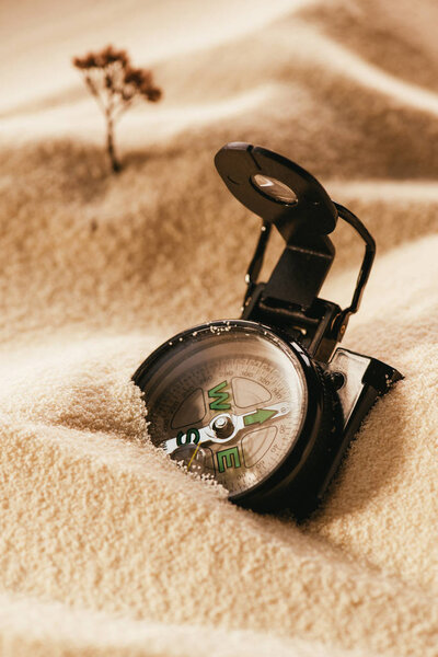 close up view of retro compass on sandy beach, traveling concept