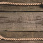 Top view of beige knotted nautical rope on wooden background