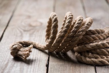 selective focus of beige knotted nautical rope on wooden background  clipart