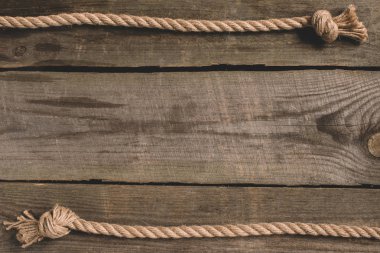 top view of beige knotted nautical rope on wooden background clipart