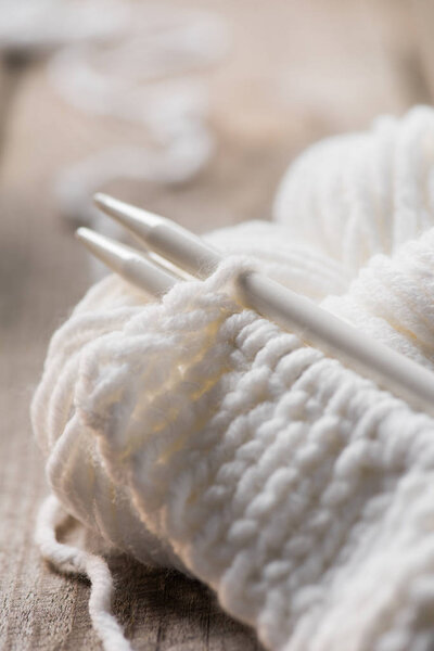 selective focus of knitted needles and white woolen knitted yarn 