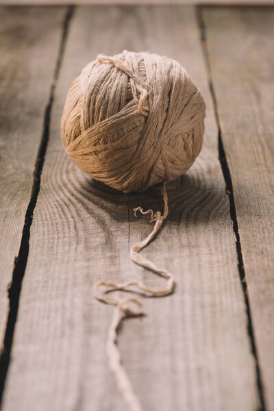 close up view of untangled beige knitted yarn ball on wooden background 