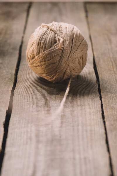 selective focus of beige knitted woolen yarn ball on wooden background 