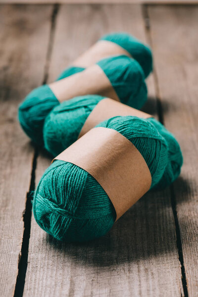 selective focus of wrapped green knitted yarn on wooden background 