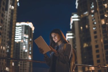 şehir geceleri sokak üzerinde dijital tablet kullanarak çekici kadın yan görünüm