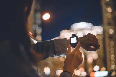 smartwatch kadınla kısmi görünümü arka plan üzerinde bilek ve gece şehir ışıkları