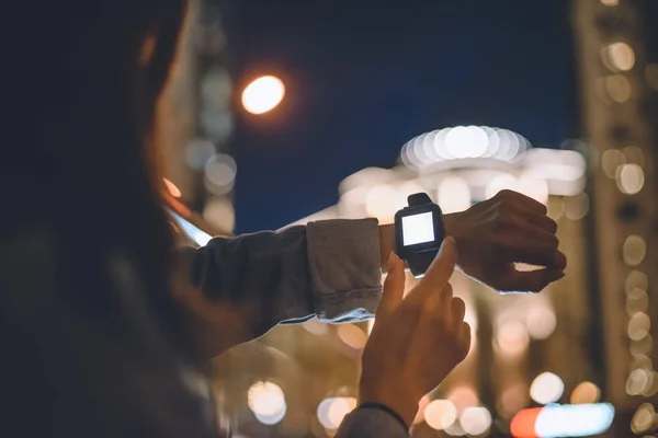 妇女的部分看法与 Smartwatch 在手腕和夜城市灯在背景 — 图库照片