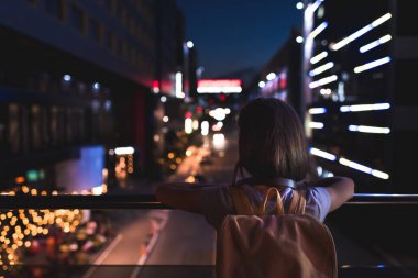 Sokakta duran ve gece şehir ışıkları seyir sırt çantası ile arkadan görünüşü kadın