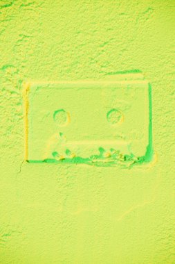 shape of retro audio cassette on light green neon background clipart