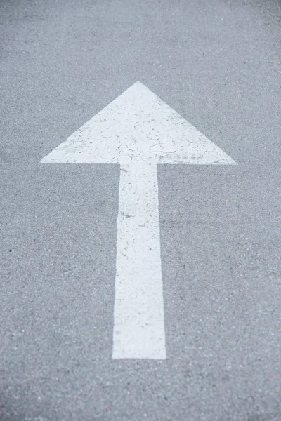 large white arrow symbol drawn on asphalt road