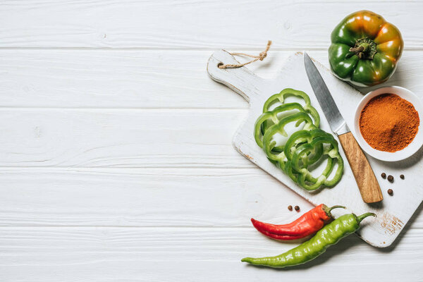 вид сверху на чили и перец, миска со специями на белом деревянном столе

