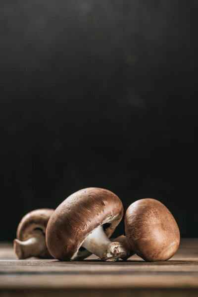 ripe portobello mushrooms on wooden table isolated on black