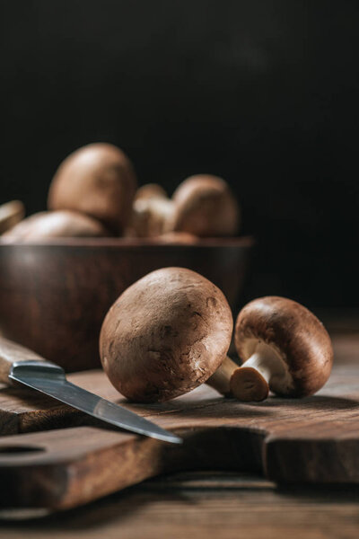 ripe portobello mushrooms and knife on cutting board isolated on black