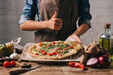 İtalyan pizza ile masa üstü, başparmak gösterilmesini önlük kadında doz kırpılmış