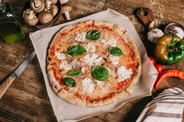 ahşap masa üzerinde İtalyan pizza, malzemeler ve bıçağı üstten görünüm