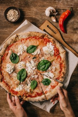 kadın alarak parça pizza kısmi görünümünü ahşap masa üzerinde kesme tahtası üzerinde