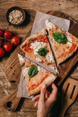 kadın alarak parça pizza kısmi görünümünü ahşap masa üzerinde kesme tahtası üzerinde